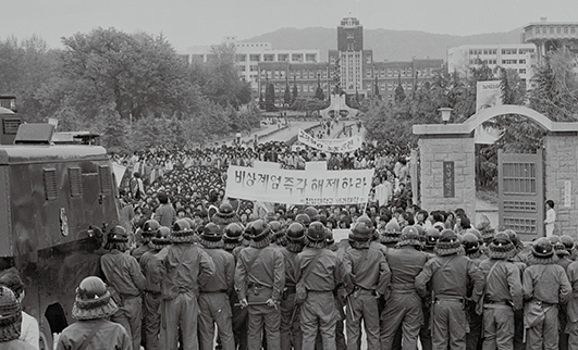 오래된 듯 보이는 흑백사진에는 전남대학교 정문을 바라보고 있는 많은 전경이 있고, 그들과 대치하는 시민들이 ‘비상계엄 즉각 해제하라, 전남대학교 의과대학이라고 쓴 현수막을 들고 있습니다. 