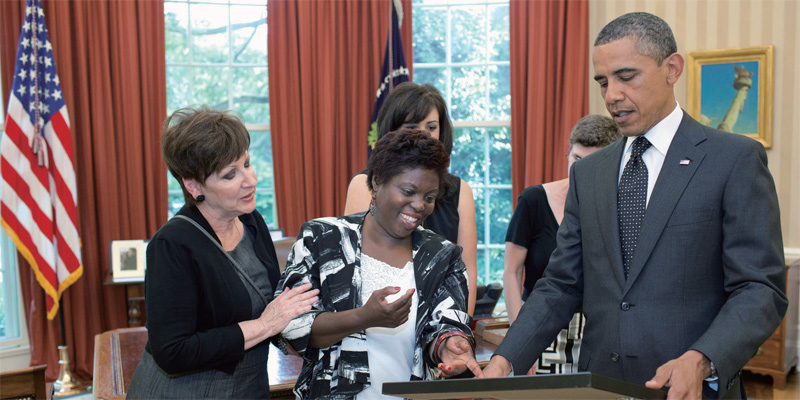 2011년 6월 20일. 옴스테드 판결 12주년을 맞아 사건 피해 당사자인 로이스 커티스(Lois Curtis, 가운데)가 오바마 대통령(오른쪽)을 만나 자신이 그린 그림을 선물로 주고 있다.(출처:백악관)